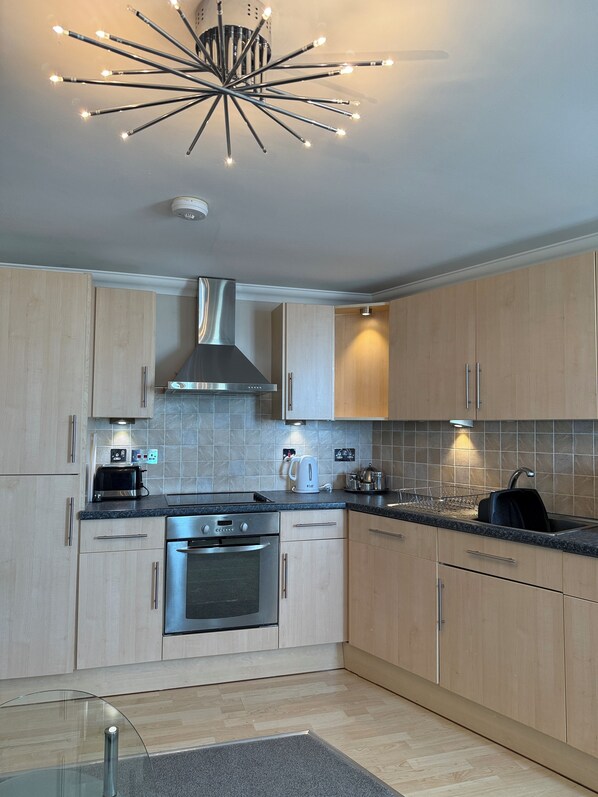 A modern kitchen with wooden cabinets, stainless steel appliances, and a unique starburst light fixture.