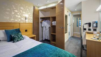 A hotel room with a bed, a desk, a wardrobe, and a bathroom.