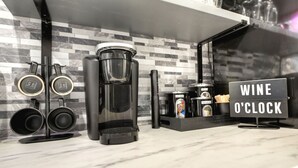 A kitchen with a coffee maker, a wine o'clock sign, and a tiled backsplash. - Luxury Suite in the heart of downtown Blue Ridge (Blue Ridge)