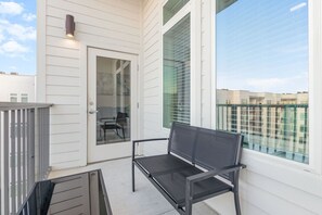 A balcony with a bench, a glass door, and a view of the cityscape. - Orlando 2BR Retreat • 3 Beds • Near Disney/Universal (Orlando)