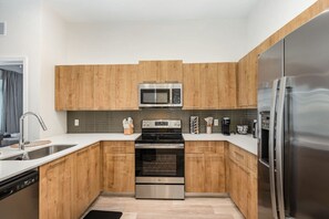 A modern kitchen with wooden cabinets, stainless steel appliances, and a dishwasher. - Orlando 2BR Retreat • 3 Beds • Near Disney/Universal (Orlando)