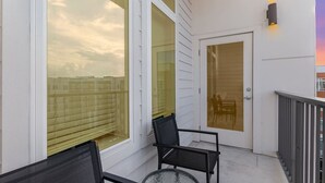 Un balcón con puerta de cristal, una silla y una mesa.