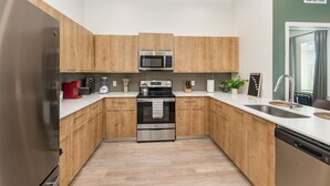 Una cocina moderna con armarios de madera, electrodomésticos de acero inoxidable y encimera blanca.