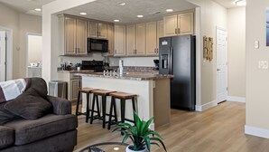 A modern kitchen with a central island, bar stools, and a refrigerator. - Par Paradise by Mesquite Vacation Rentals with Views of the Fairways and $510 in free daily activities (Mesquite)
