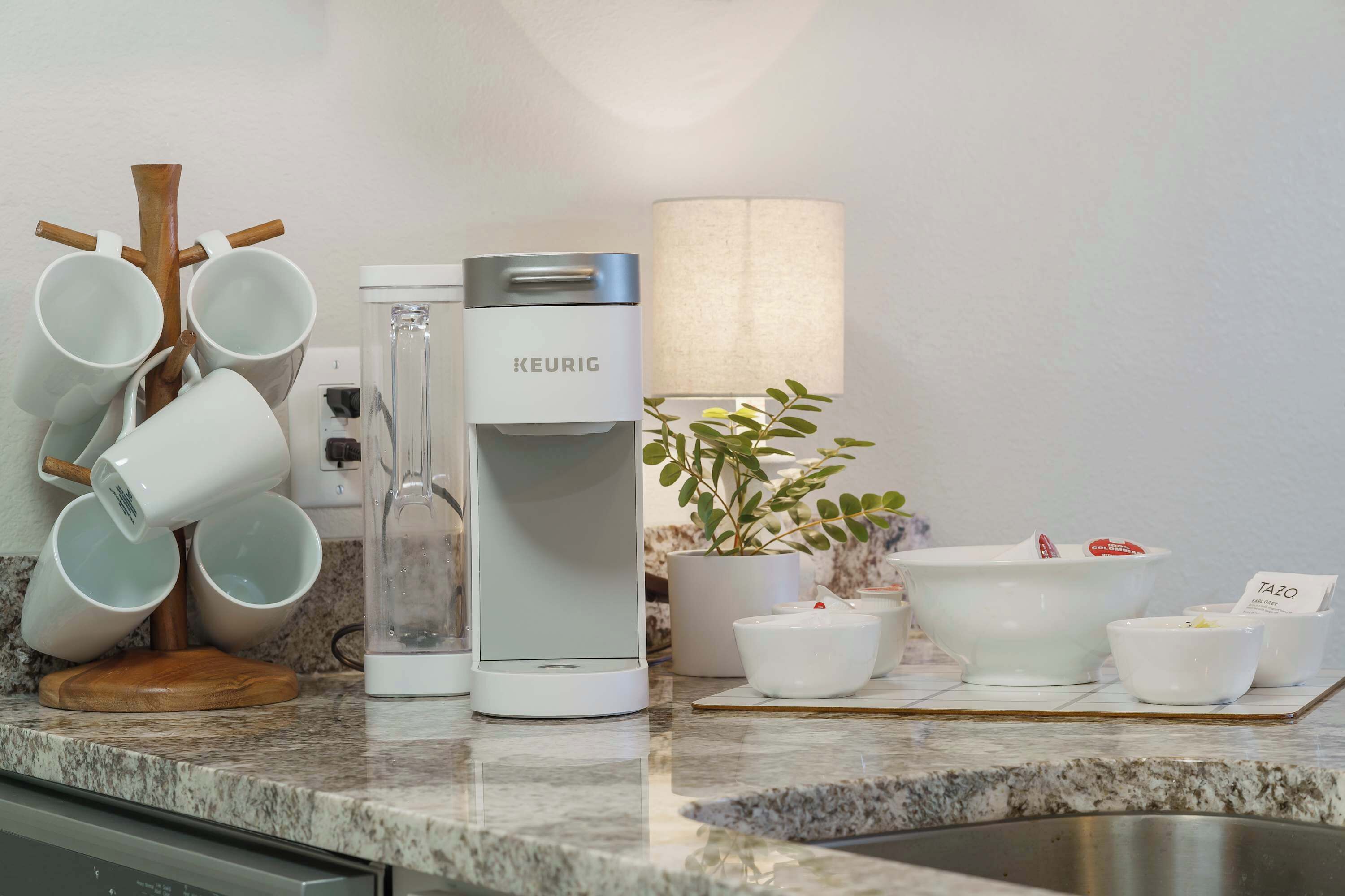 A kitchen with a coffee maker, a plant, and a coffee machine.