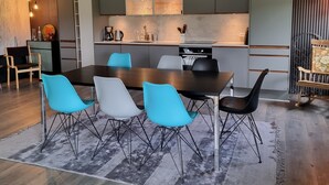 A modern kitchen with grey cabinets, a central island, and a dining area with a wooden table and blue chairs.