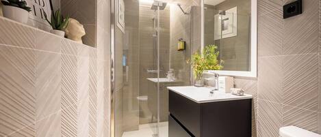 A modern bathroom with a glass-enclosed shower, a black vanity, and a large mirror.