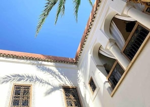 Un edifici amb façana blanca, diverses finestres amb reixes decoratives i teulada de rajoles vermelles.