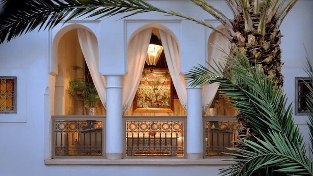 A building with three arched windows, each with a decorative railing and a potted plant. - Riad Douceur (Marrakech)