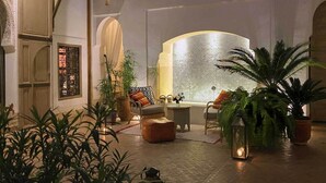 A cozy lounge area with seating, potted plants, and a decorative wall. - Riad Douceur (Marrakech)