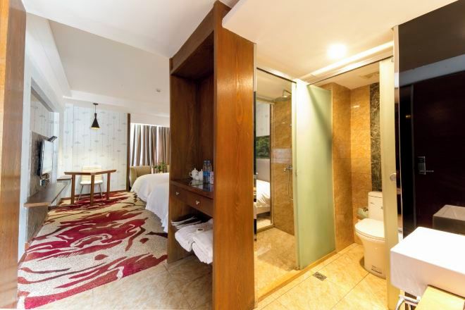 Una habitación de hotel con cama, armario de madera, zona de ducha y baño.
