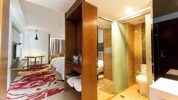 Una habitación de hotel con cama, armario de madera, zona de ducha y baño.