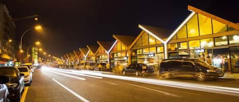 Eine Straße gesäumt von modernen Gebäuden, Fahrzeugen und Straßenlaternen bei Nacht.