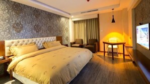 A hotel room with a large bed, a desk, two chairs, a TV, and a patterned wall. - Zhoushan Shenjiamen Zhongjing Hotel(Banshengdong Passenger Terminal Branch) (Zhoushan)