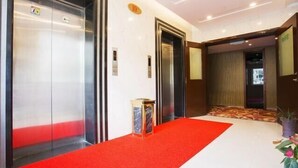 A hotel lobby with two elevators, a red carpet, and a small table with a vase of flowers. - Zhoushan Shenjiamen Zhongjing Hotel(Banshengdong Passenger Terminal Branch) (Zhoushan)