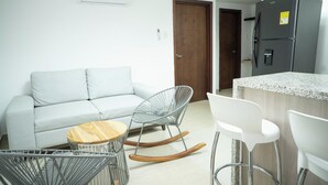 A modern kitchen with a refrigerator, a dining area with a sofa and chairs, and a small wooden table. - 2-bedroom apartment in Bocagrande- Cartagena (Bolívar)
