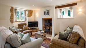 A cozy living room with a fireplace, comfortable seating, and a television. - Pickett Cottage - Pet friendly near Northleach (Northleach)