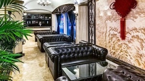A luxurious lounge area with leather sofas, a glass coffee table, and a marble floor. - Jiuyuan Hotel (Jiuzhaigou)