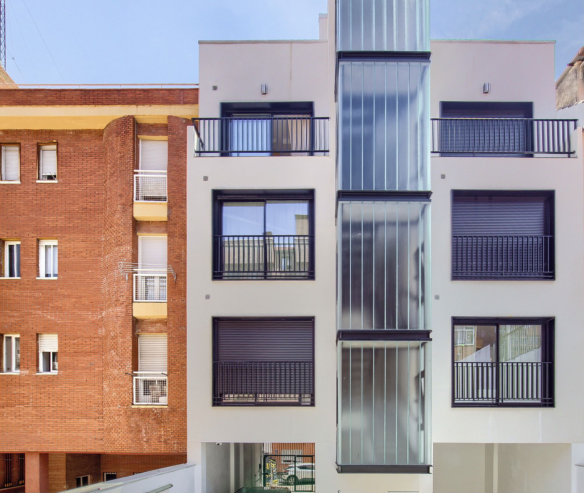 Un edificio de varios pisos con una combinación de fachada de ladrillo y diseño moderno, que cuenta con balcones con barandas de metal y grandes ventanales.