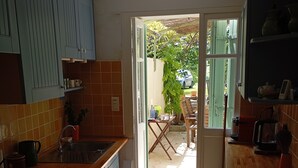 A kitchen with a gas stove, sink, and cabinets. There is a door leading to an outdoor area with a table and chairs.