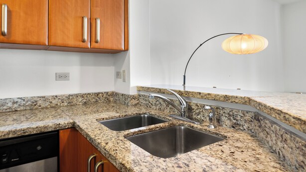 A kitchen with granite countertops, stainless steel sinks, wooden cabinets, and a modern pendant light. - Golf Course Access Balcony Infinity Pool (Fajardo)