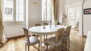 A round dining table with four chairs, a window with curtains, and a lamp on the wall. - Charming Apartment in the Heart of Florence (Firenze)