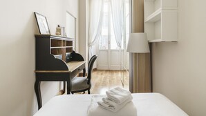 A hotel room with a bed, a desk, a chair, a lamp, and a wardrobe. - Charming Apartment in the Heart of Florence (Firenze)