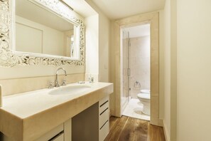A bathroom with a large mirror, a sink, and a shower area.