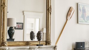 A room with a white marble fireplace, a large ornate mirror, and a wooden paddle leaning against the wall. - Charming Apartment in the Heart of Florence (Firenze)