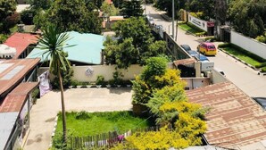 A residential area with various buildings, including a multi-story structure under construction, surrounded by greenery and parked cars. - Shalla Guesthouse and Wellness Center (Addis Ababa)