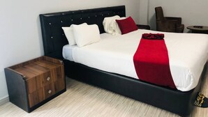 A bed with a black headboard, white bedding, and a red throw. There is a wooden chest of drawers beside the bed. - Shalla Guesthouse and Wellness Center (Addis Ababa)
