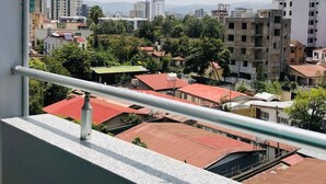 A balcony with a metal railing overlooking a cityscape with various buildings and greenery. - Shalla Guesthouse and Wellness Center (Addis Ababa)