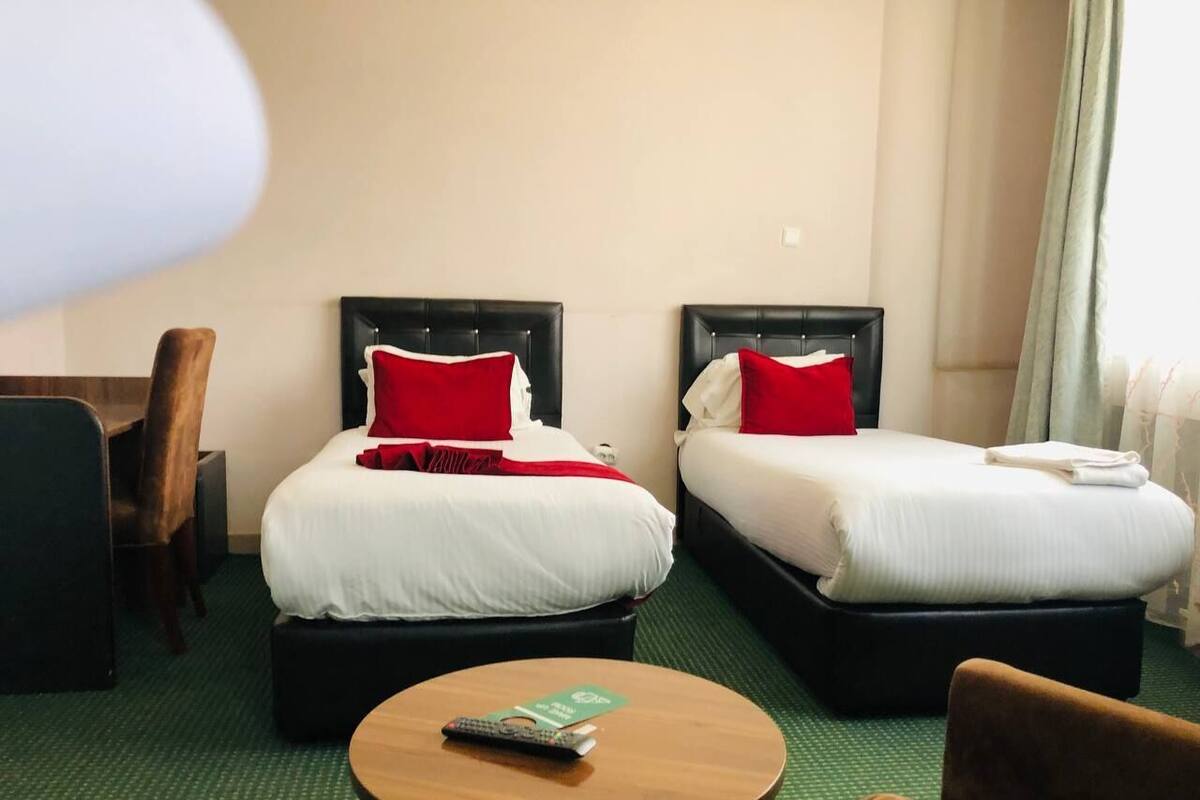 A hotel room with two beds, a round table, and a chair.