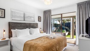 Une chambre d’hôtel moderne dotée d’un grand lit, d’un téléviseur à écran plat et d’une porte-fenêtre coulissante donnant sur l’extérieur.