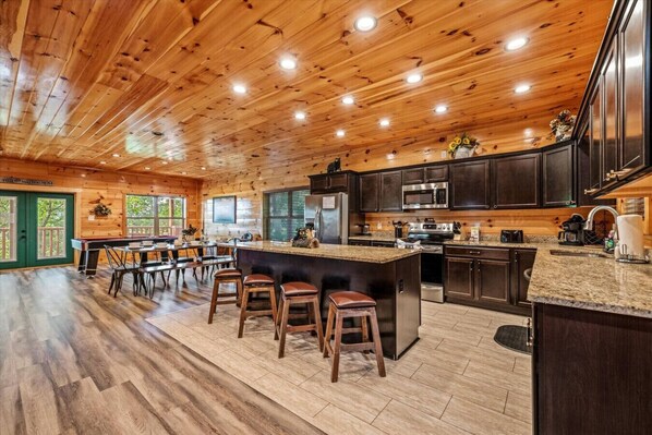 A spacious kitchen with a large island, dark wooden cabinets, and a granite countertop.