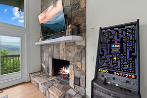 Ein Kamin aus Stein mit einem Fernseher darüber und einer Spielkonsole daneben.