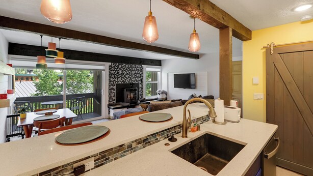 Une cuisine dotée d’un grand îlot central, de luminaires suspendus, d’une cuisinière intégrée et offrant une vue sur l’extérieur.