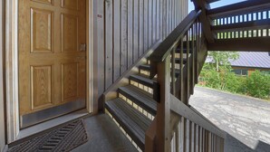 Une porte en bois avec une poignée en métal, un escalier en bois avec une rampe et une balustrade en bois sur le porche.