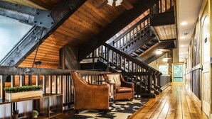 Un loft espacioso con piso de madera, sillones de cuero, una escalera y vistas al exterior.