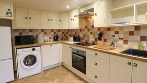 Una cocina compacta equipada con lavadora, microondas, horno y lavabo.
