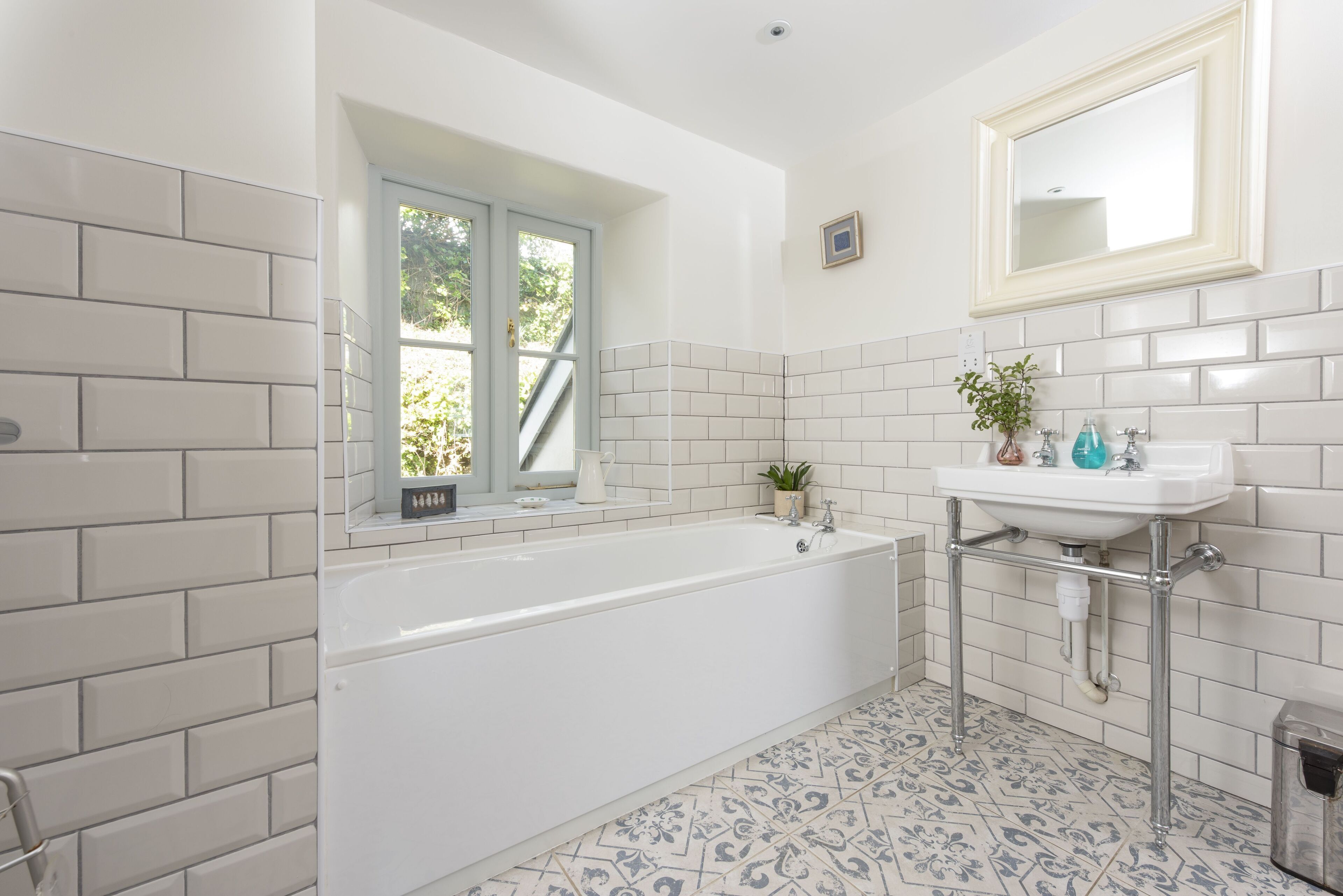A bathroom with a bathtub, a sink, and a window.