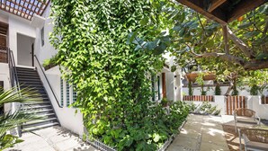 Un patio con cerca blanca, una escalera de madera y una zona de estar con sillas.
