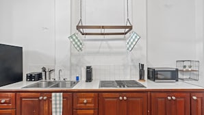 Une cuisine avec des meubles en bois, un évier, une cuisinière, un four à micro-ondes et une balançoire suspendue dotée de coussins à carreaux.