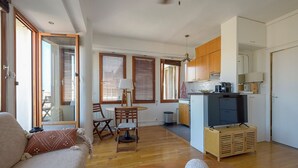 A compact living space with a sofa, dining table, chairs, a TV, and a kitchen area. - Cosy studio with terrace overlooking Marseille (Marseille)