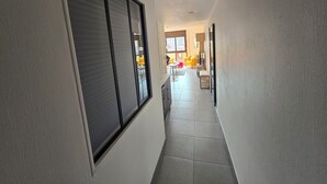Un pasillo con puerta corrediza, suelo de baldosas y vista a un área de estar amoblada.