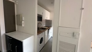 Cocina compacta con lavadora, microondas y horno integrado.