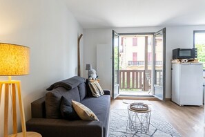 A modern living room with a sofa, lamp, and a view of a balcony.