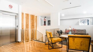 En moderne lobby med trægulv, trappe, sofa og sofabord.