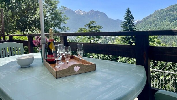 A table with a bottle of champagne, glasses, and a bowl on a terrace with a mountain view. - Apartment for 4 with with nice view of Briançon (Briançon)