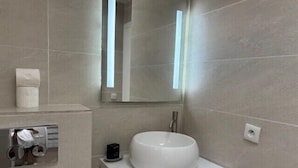 A modern bathroom with a white sink, a mirror, and a towel dispenser. - Beautiful 41 m² with balcony (Antibes)
